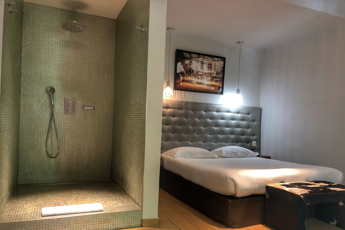 Un baño moderno con ducha y cama con cabecero capitonado.