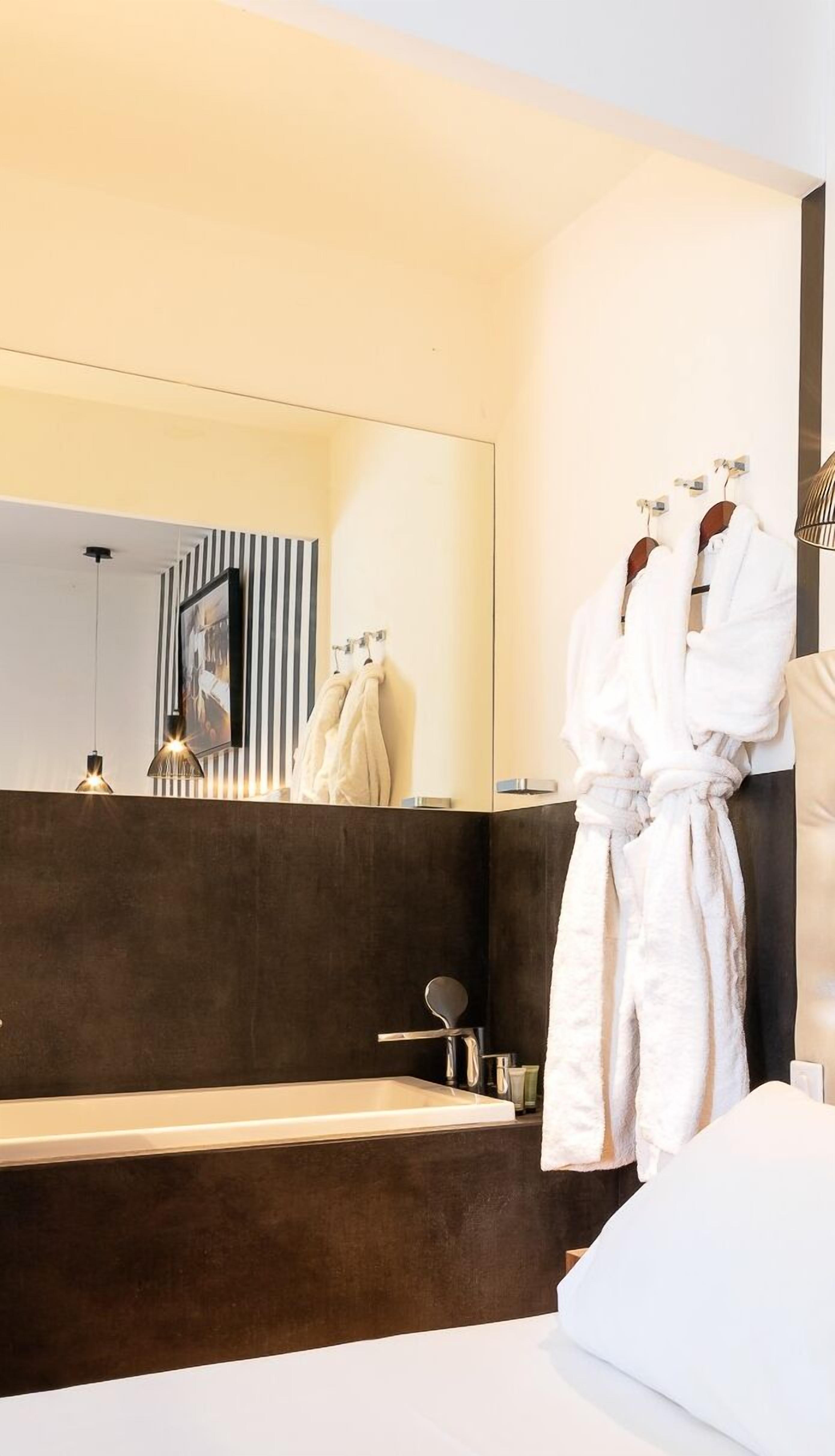 Un baño moderno con un espejo grande, una bañera y una bata colgada en un perchero.