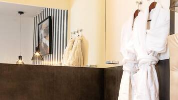 A modern bathroom with a large mirror, a bathtub, and a robe hanging on a rack.