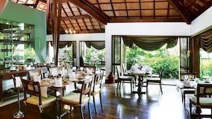 Un restaurante con mobiliario de madera, ventanas amplias y vistas a zonas verdes.