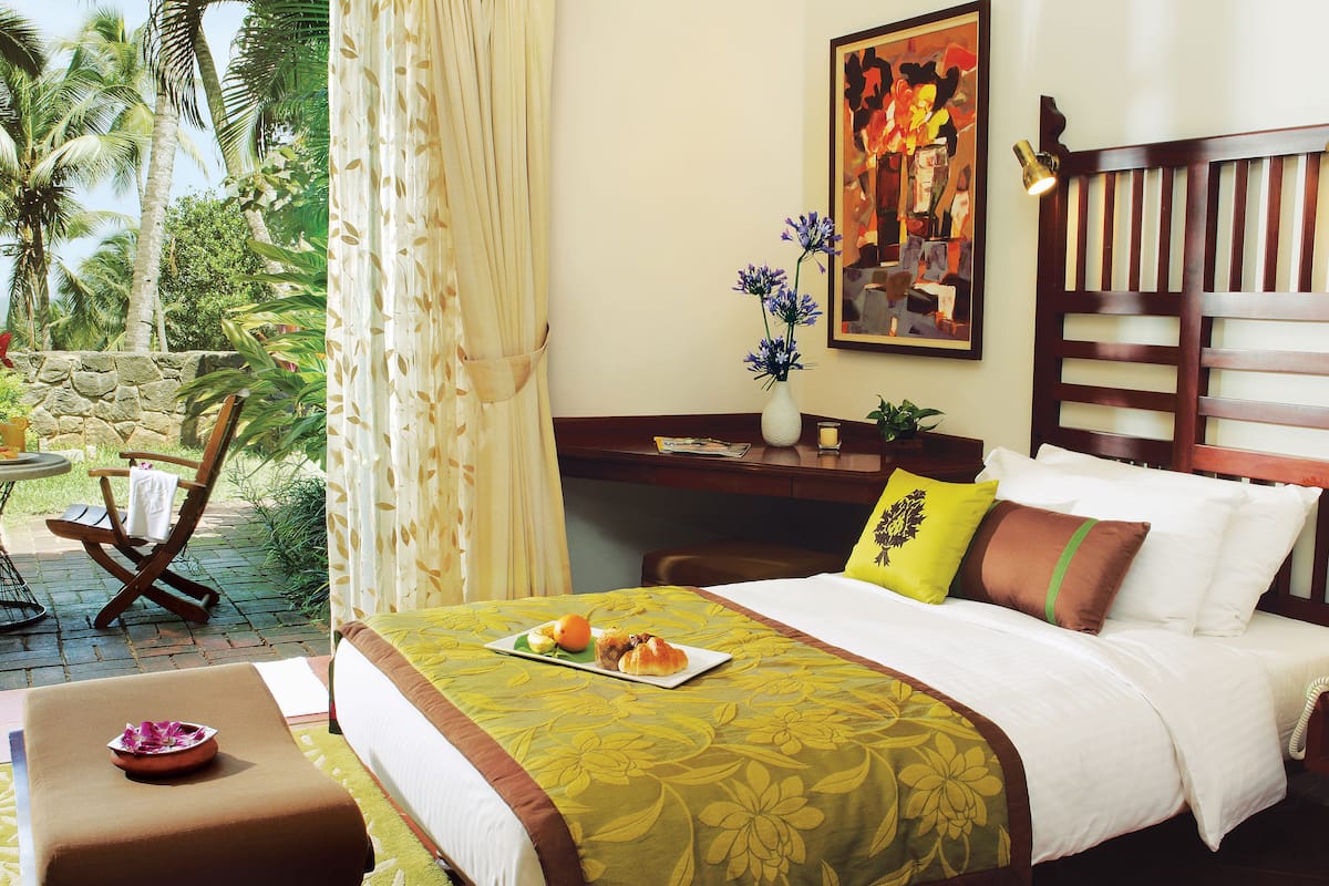 A hotel room with a bed, a desk, a chair, and a view of palm trees.