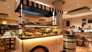 A food cart labeled 'dela TIERRA' with a variety of baked goods and a barrel.