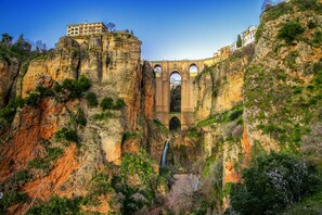 A historic stone bridge with arches, a building on top, and a waterfall.