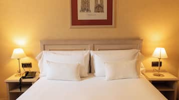 Una habitación de hotel con una cama grande, dos mesitas de noche, un teléfono y dos lámparas.
