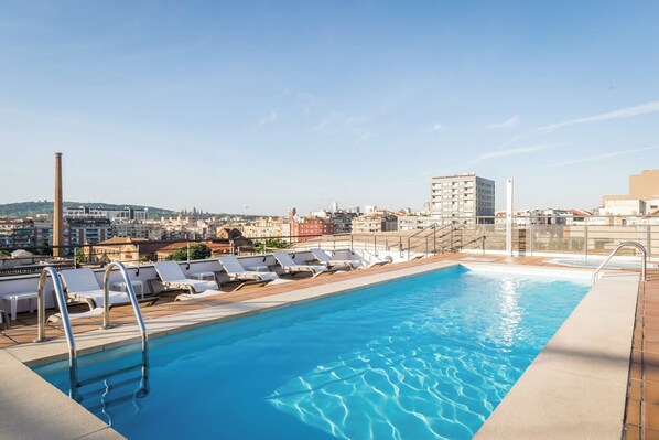 A rooftop pool with sun loungers and a cityscape view. - Sunotel Aston (Barcelona)