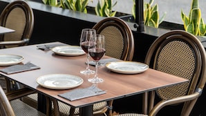 A dining table set with plates, cutlery, and wine glasses, surrounded by wicker chairs. - Sunotel Aston (Barcelona)