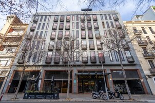 A building with multiple balconies, a storefront with a sign reading "Sunotel Astoria," and a motorcycle parked in front.