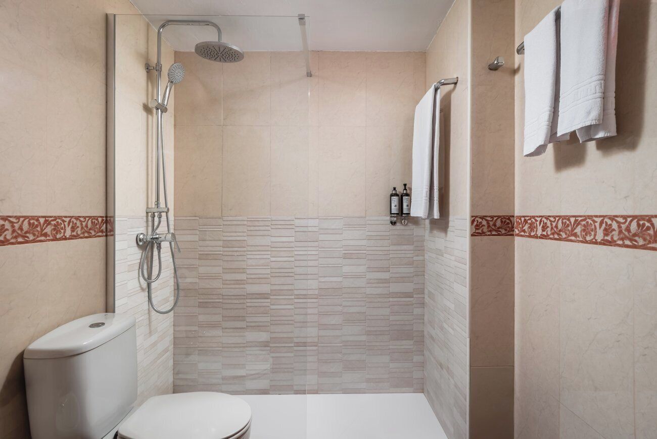 Un baño con ducha, inodoro y perchero.