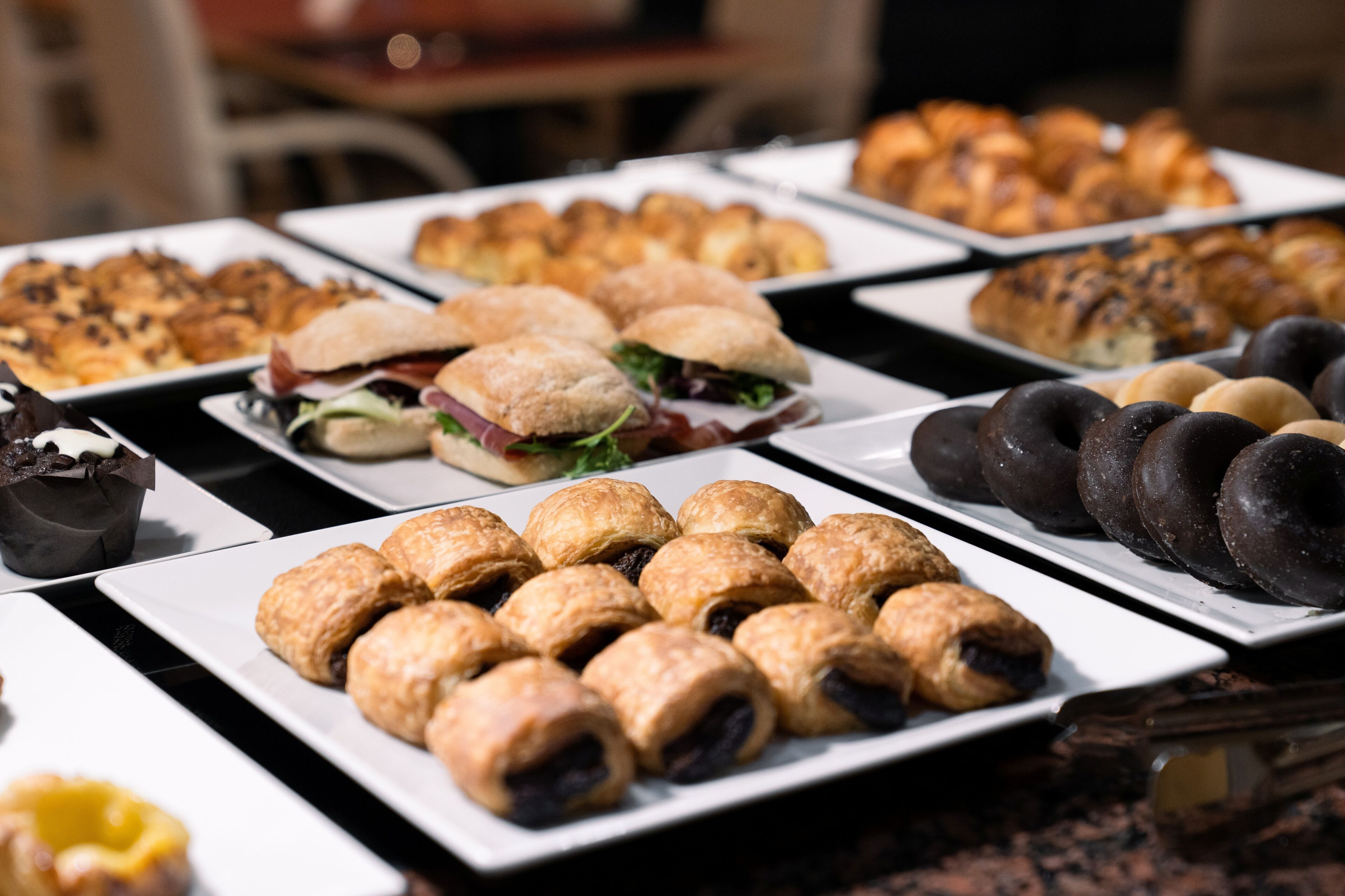 A buffet with various pastries, sandwiches, and desserts.