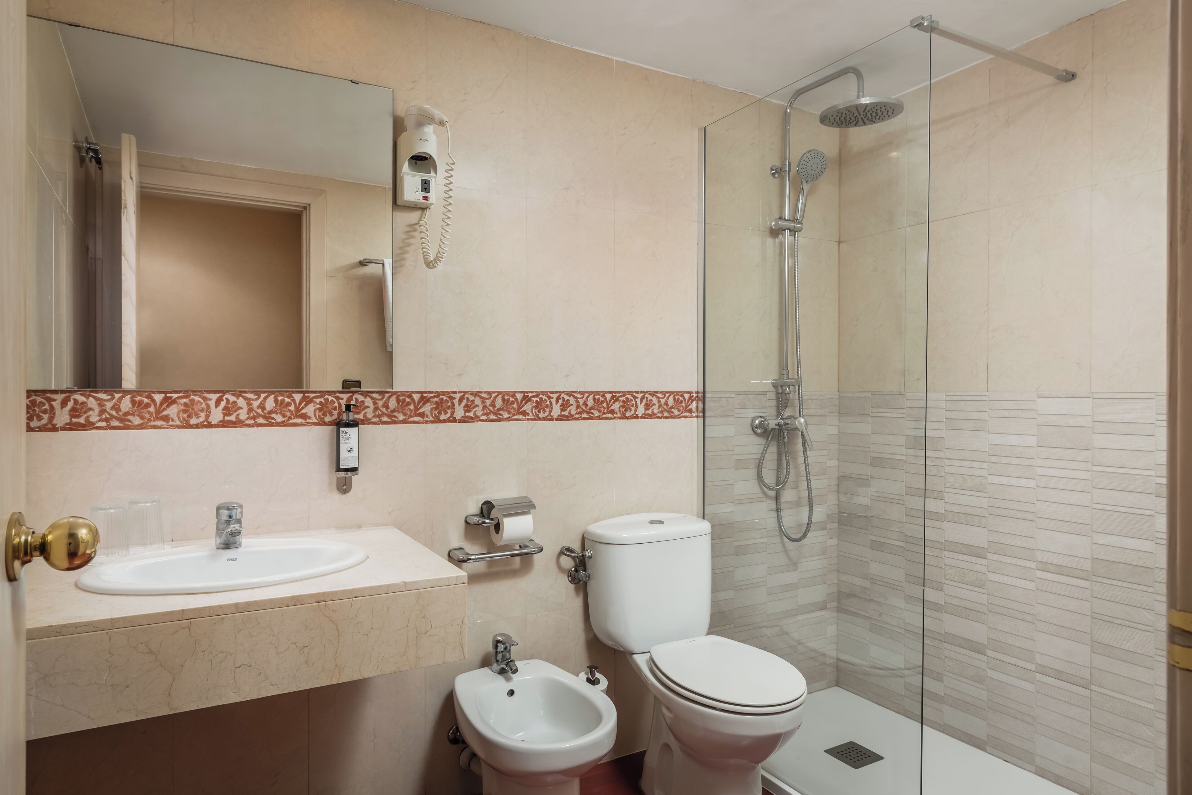 A bathroom with a sink, bidet, toilet, and glass-enclosed shower.