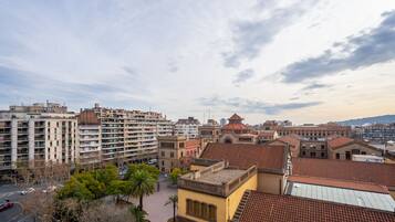Paisagem urbana com vários edifícios, incluindo uma construção com telhado vermelho e diversos prédios de vários andares com sacadas.