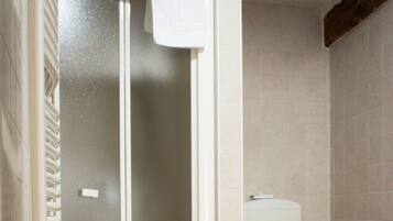 Ein Badezimmer mit Duschkabine, Toilette und einem Schachbrettmuster-Boden.