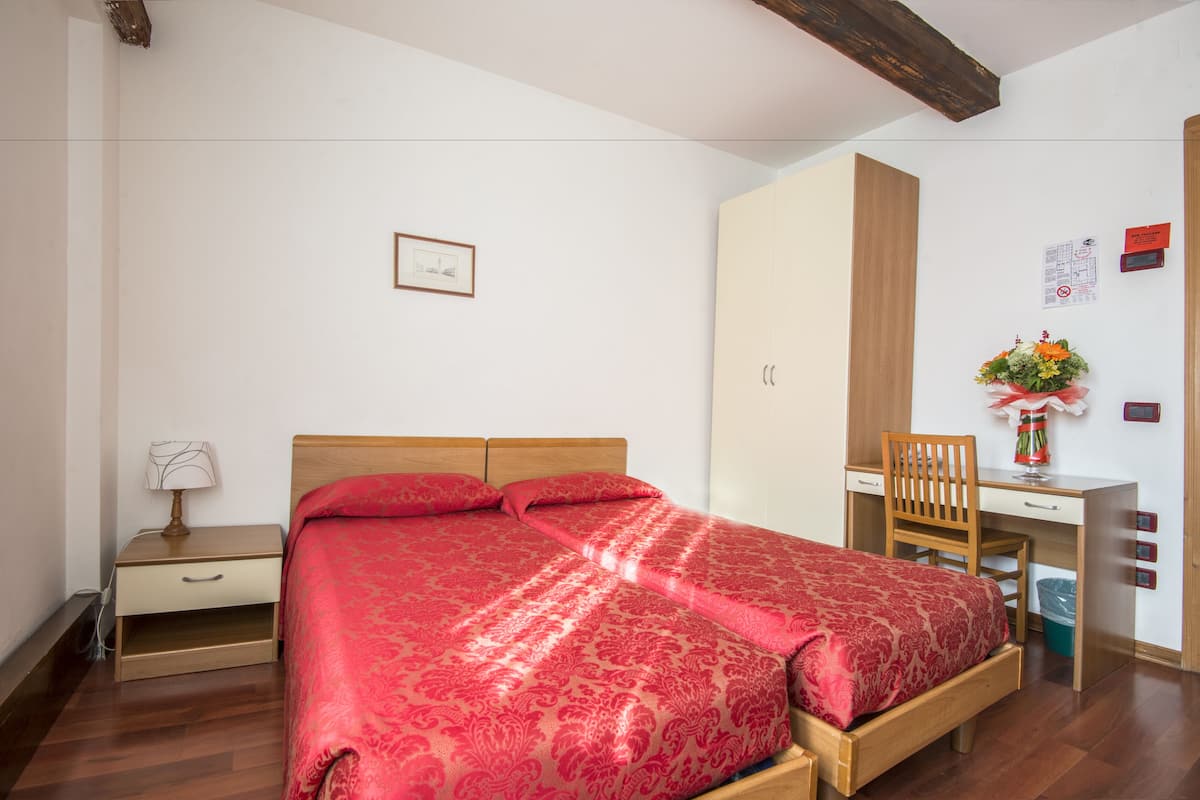 A bedroom with a bed, a desk, a chair, and a wardrobe.