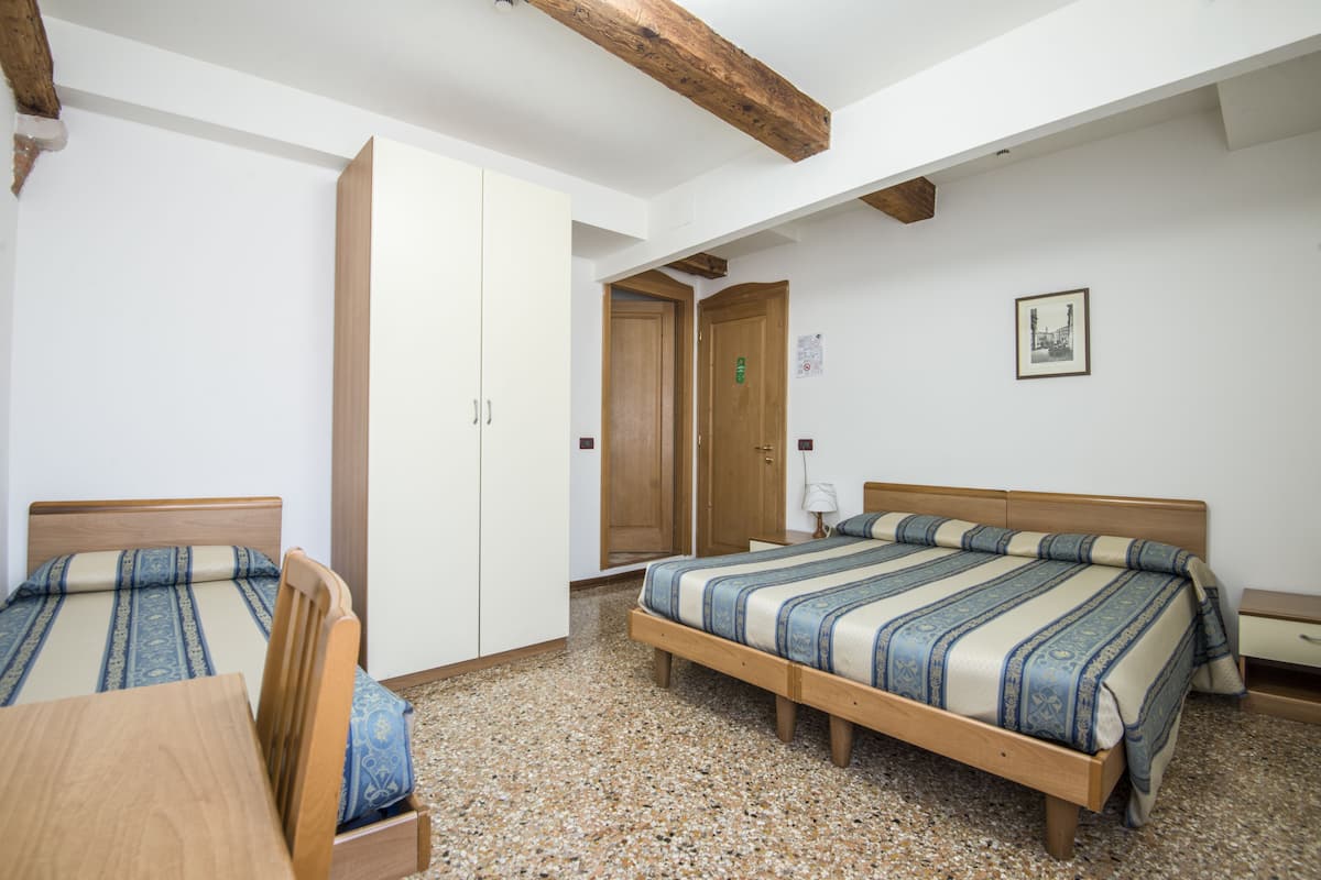 A bedroom with two beds, wooden furniture, a wardrobe, and a framed picture on the wall.