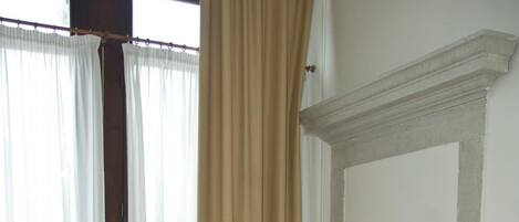 A hotel room with two beds, a wooden chair, a nightstand, and a window with curtains.
