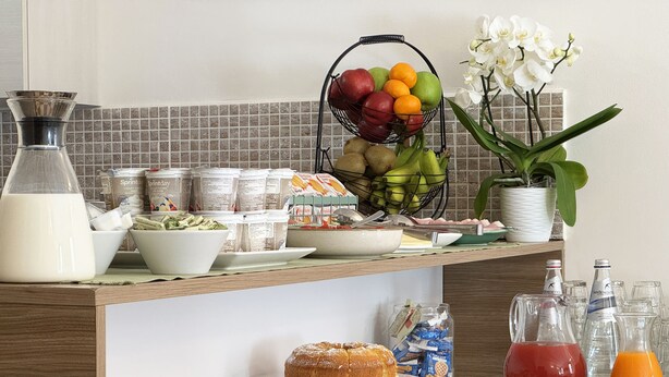 Um buffet de café da manhã com diversas opções de alimentos, incluindo frutas, pães e bebidas.