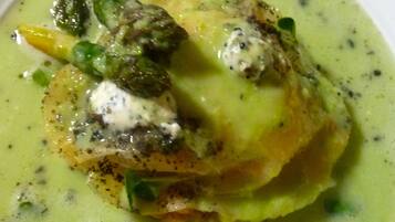 A dish with a creamy green sauce, green vegetables, and a dollop of white sauce on top.