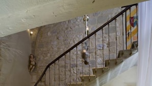 Un escalier menant à une pièce où se trouvent un bureau et une chaise, une lampe et une pancarte sur laquelle on peut lire « La Cortejos ».