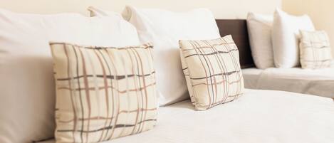 A bed with white bedding and two plaid pillows.