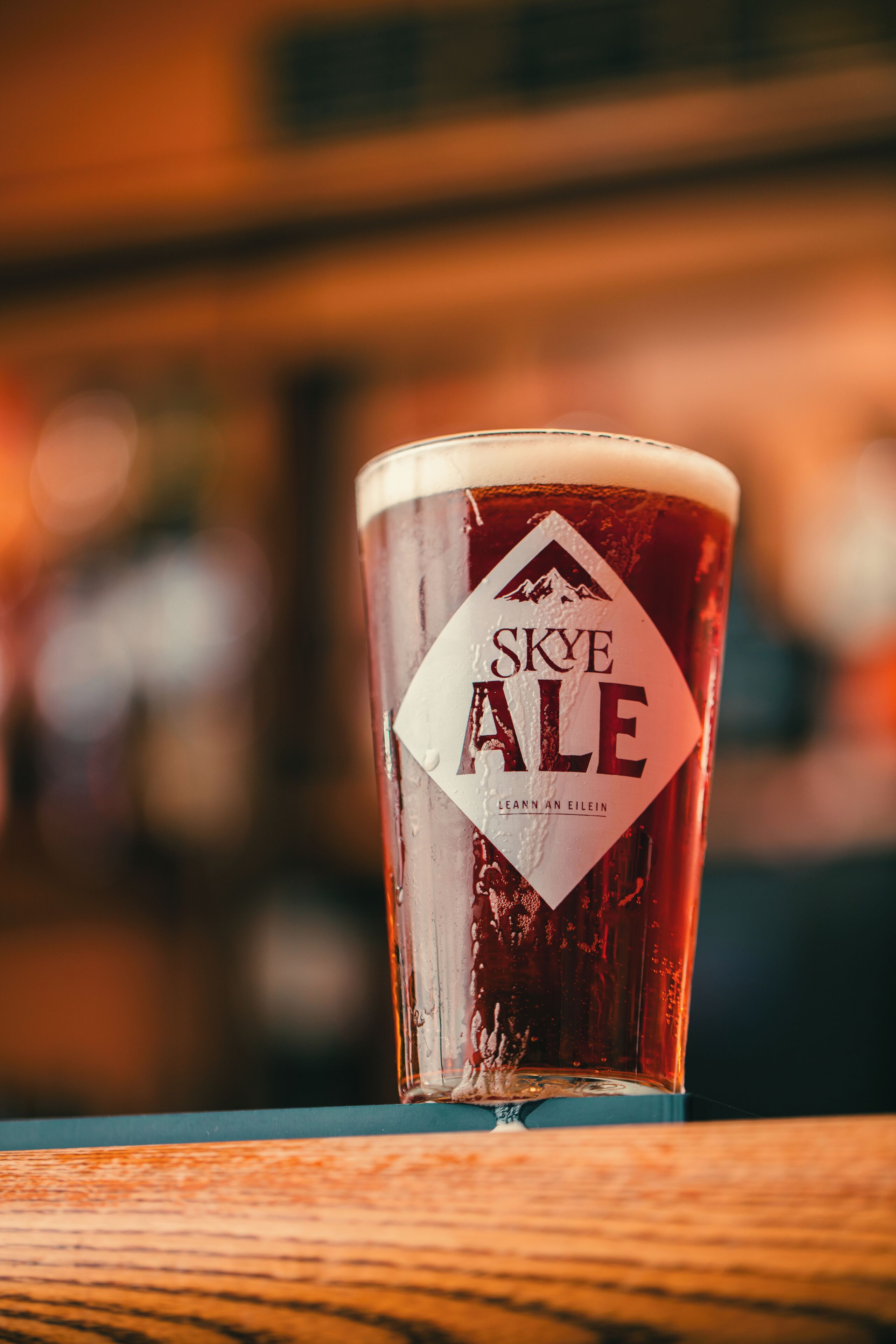 Una jarra de cerveza Skye Ale con un logotipo de montaña, sobre una superficie de madera.