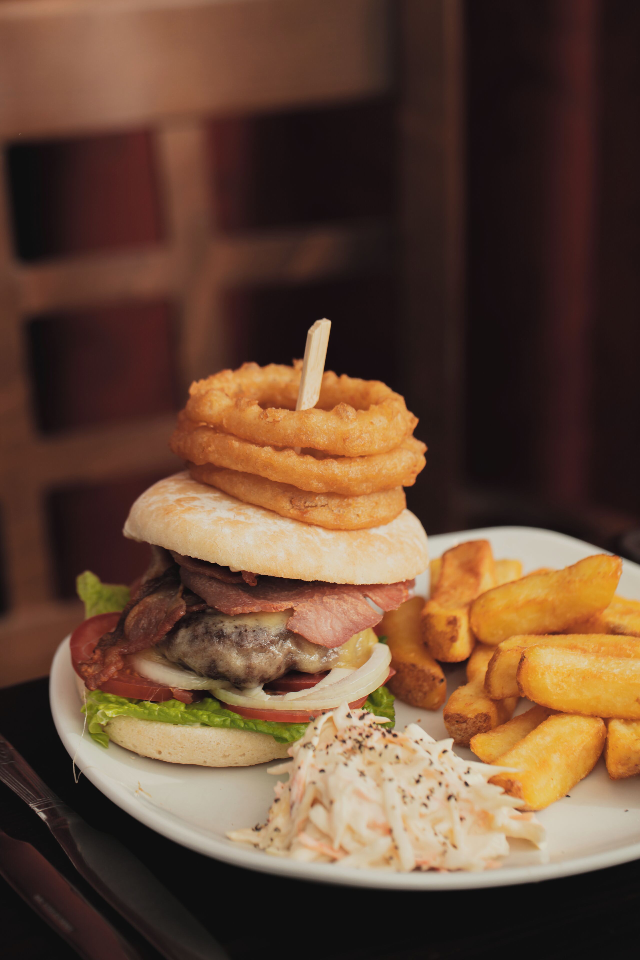 Une assiette comprenant un hamburger, des rondelles d’oignon panées, des frites et de la salade de chou.