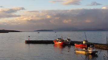 A calm harbor with several boats docked near a stone pier.