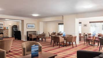 Un hall de hotel con chimenea, comedor y asientos.