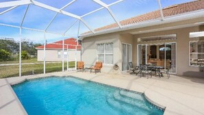 A covered outdoor swimming pool with a patio area, including seating and a table.