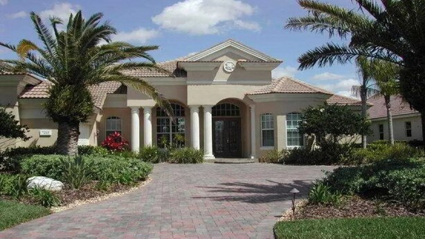 A two-story house with a central entrance, columns, and a tiled roof.