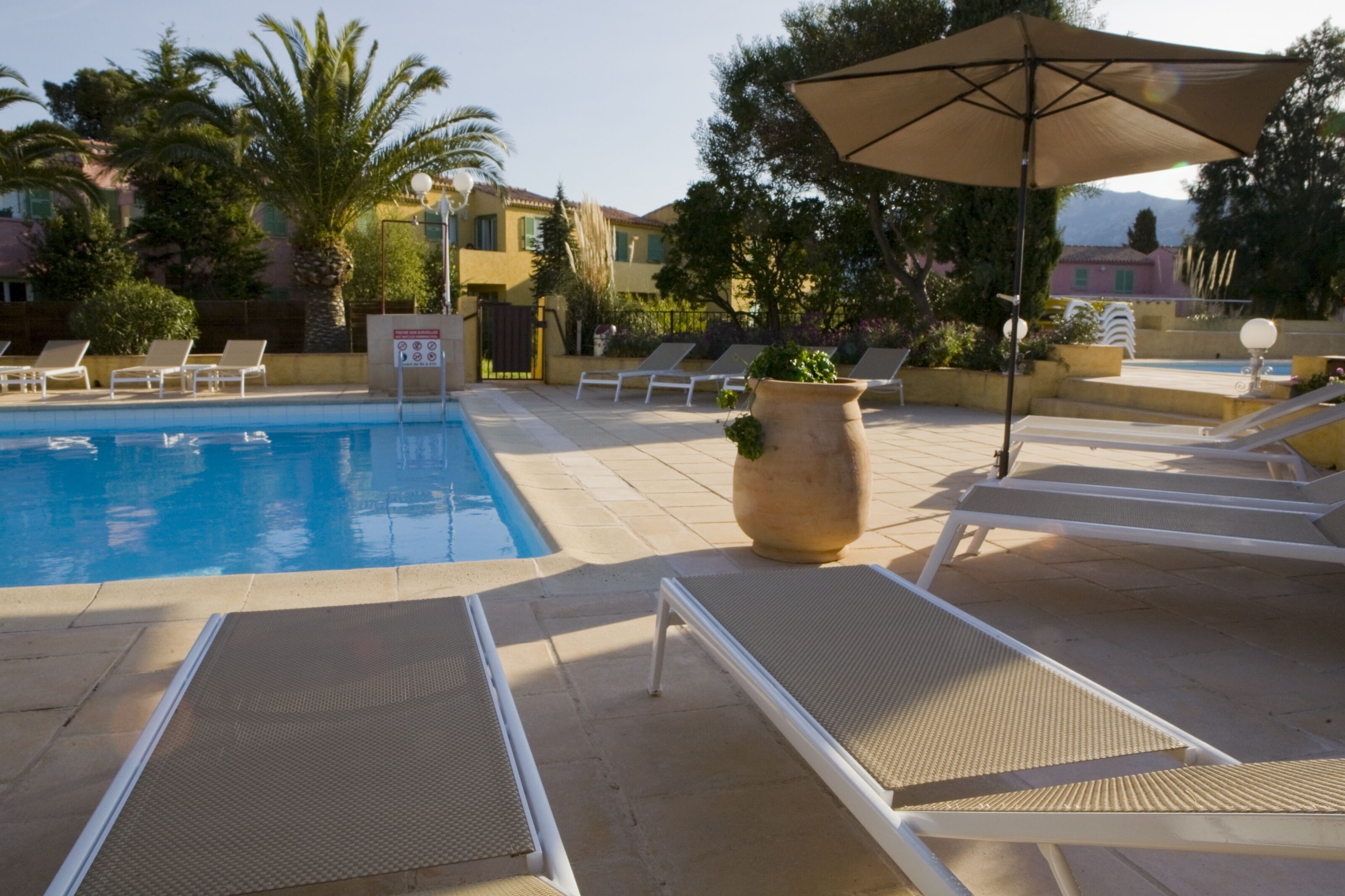 A pool area with lounge chairs and umbrellas.