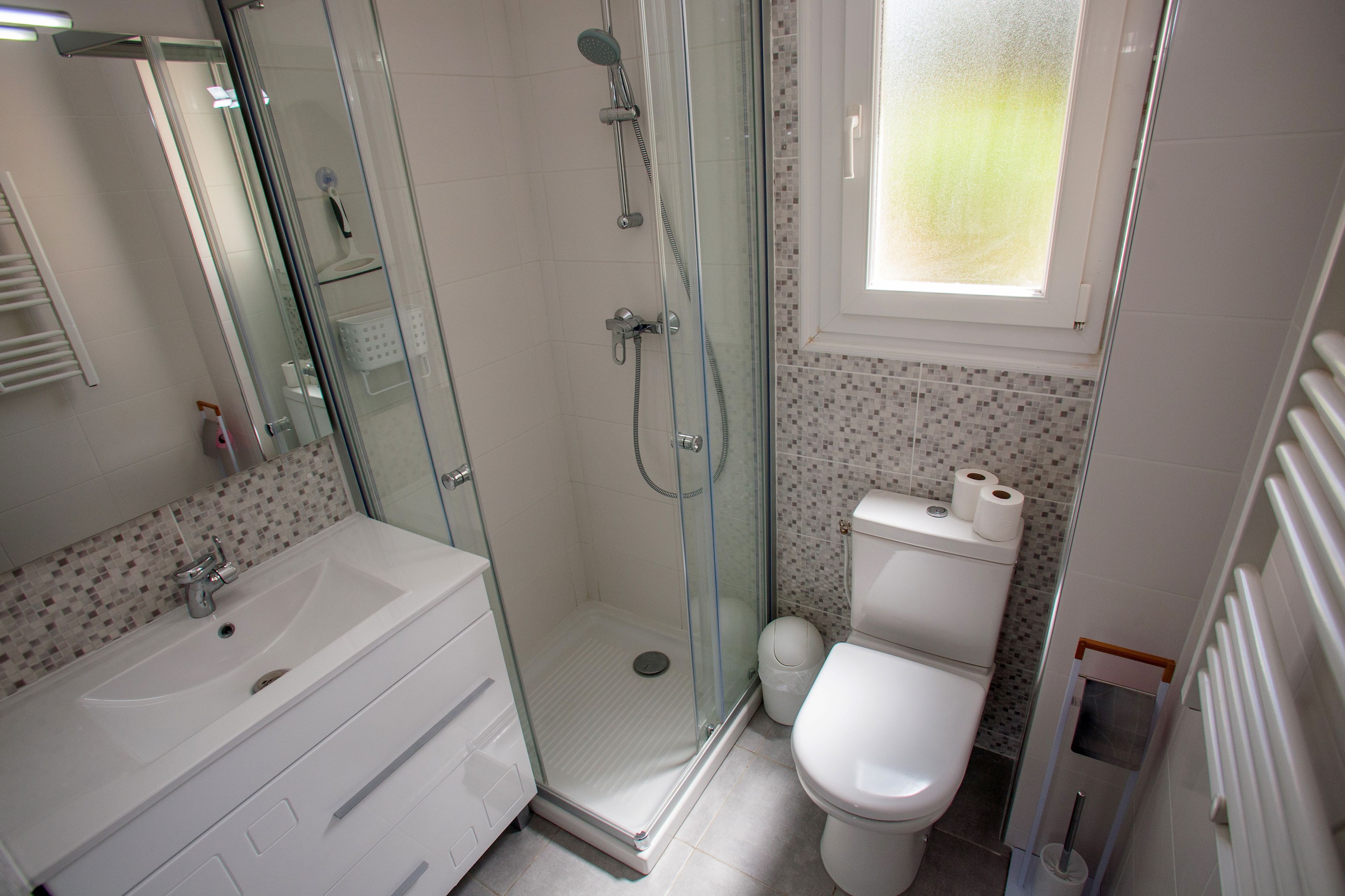 Une salle de bain avec une douche à parois de verre, un lavabo blanc et des toilettes.