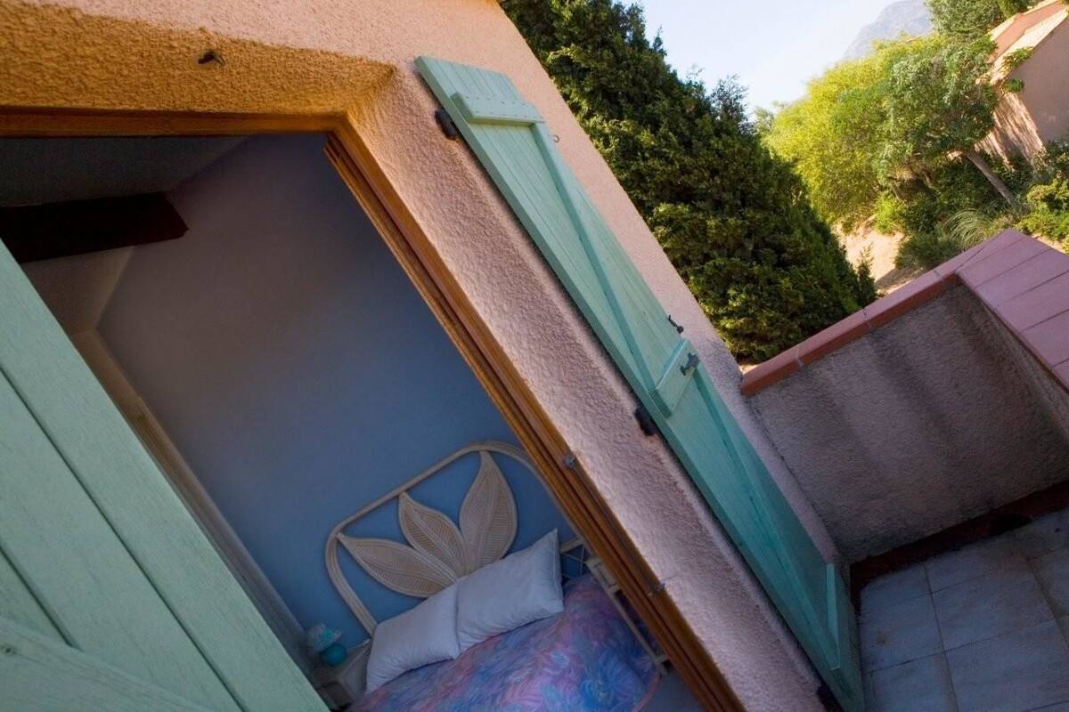 Un dormitorio con cama, ventana y vista a espacios verdes.