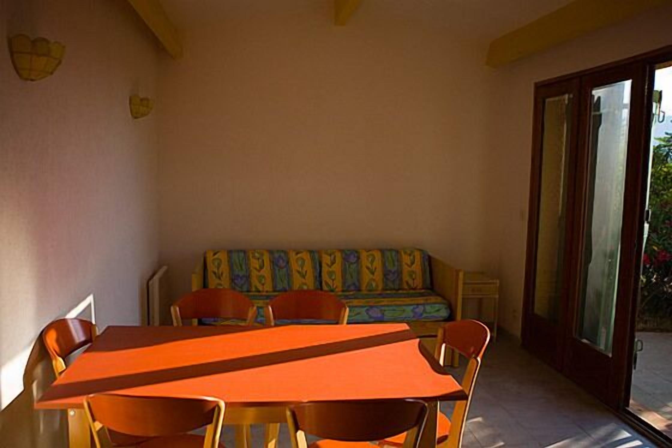 Un comedor con una mesa y sillas, un banco y un ventanal de vidrio que da al exterior.
