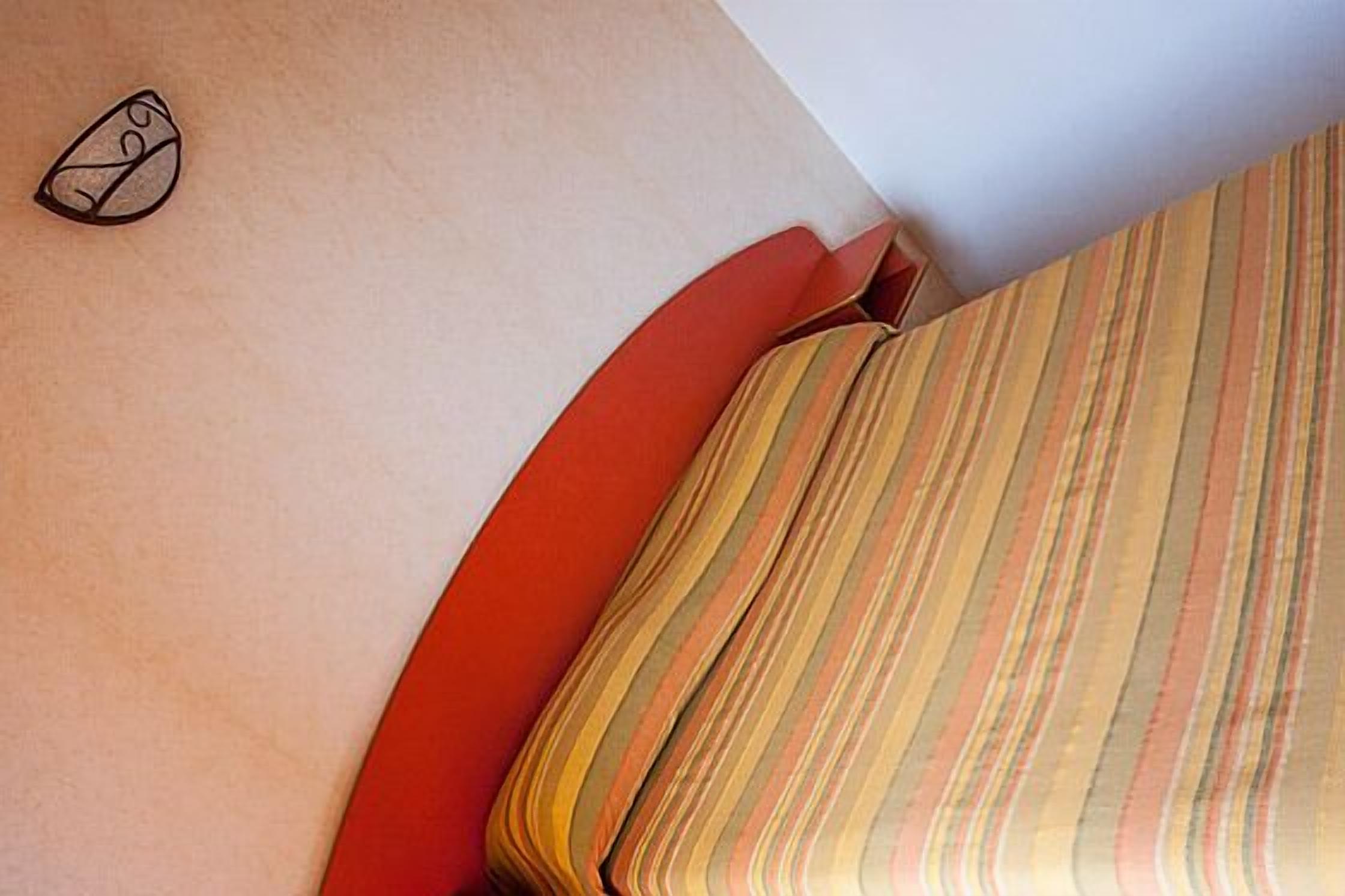 Ein Bett mit gestreifter Bettwäsche und einem Kopfkissen mit geometrischem Muster.
