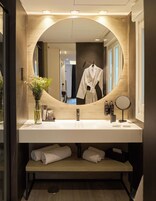 Ein modernes Badezimmer mit einem großen Spiegel, einem weißen Waschbecken und einer hölzernen Waschtischbank.