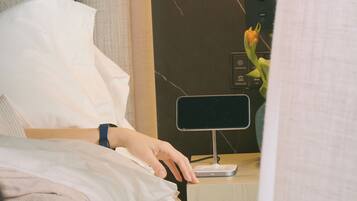 A hotel room with a bed, a bedside table with a lamp, and a wall-mounted air purifier.