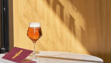 Ein Glas bernsteinfarbenes Bier auf einem Marmortisch mit Holz im Hintergrund.