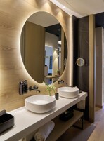 Ein modernes Badezimmer mit einem großen Spiegel, zwei Waschbecken und einem Handtuchhalter.