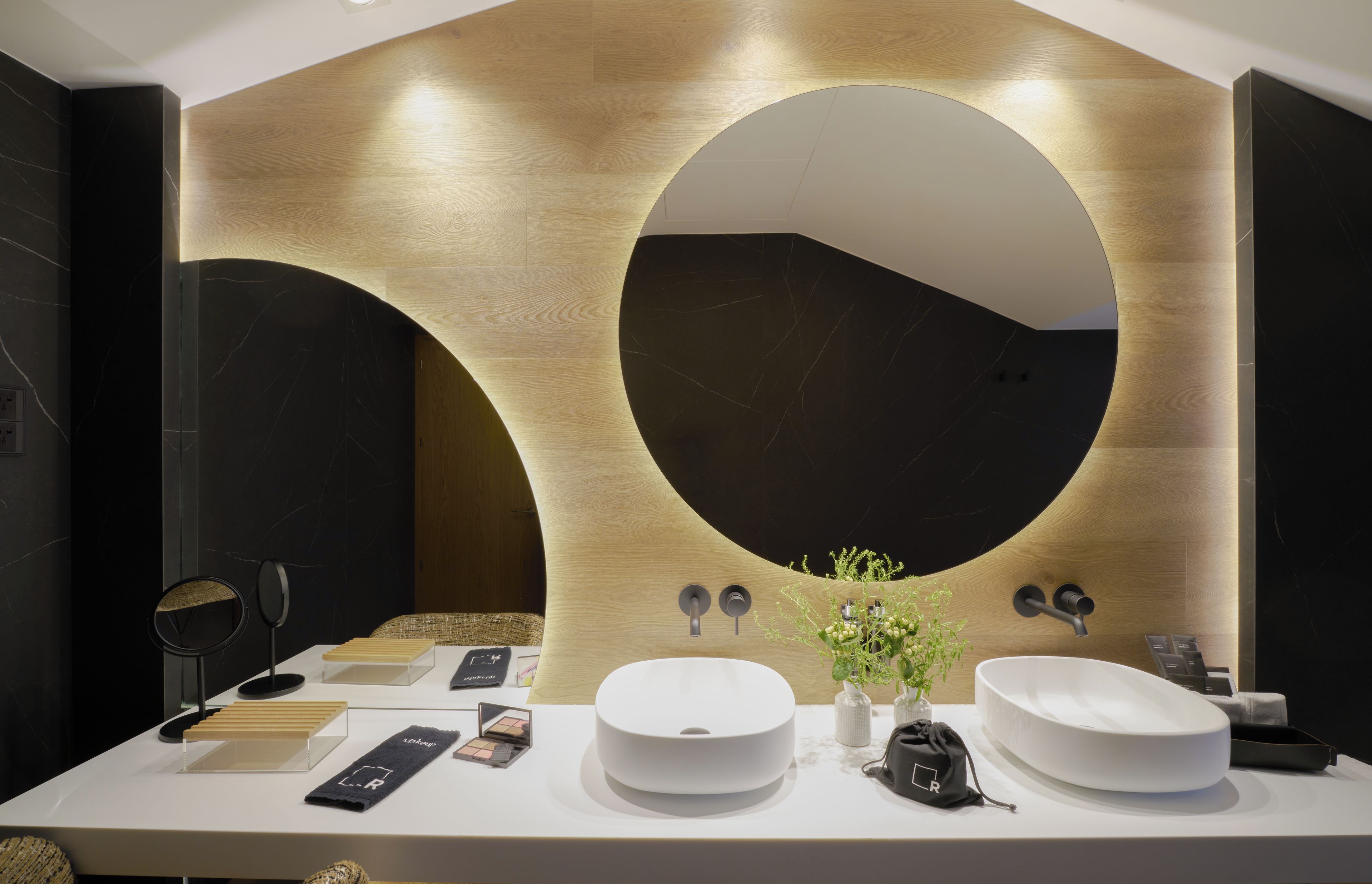 Un baño moderno con dos lavabos, un espejo grande y un diseño de pared de madera.