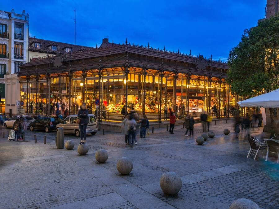 A historic building with a glass facade, surrounded by cobblestone pavement and stone bollards.
