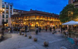 Ein historisches Gebäude mit Glasfassade, umgeben von Kopfsteinpflaster und Steinpfählen.
