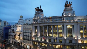 Ein historisches Gebäude mit klassischer Architektur, großen Fenstern und Statuen auf dem Dach.