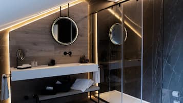 Een moderne badkamer met een houten wastafelmeubel, een douchecabine van glas en een ronde spiegel.