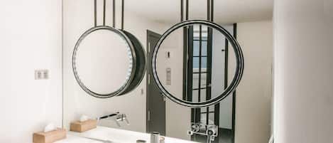 Un bagno moderno con due ampi specchi, un lavandino bianco e un porta asciugamani in legno.