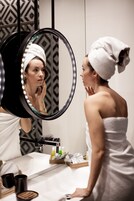 Ein Badezimmer mit Spiegel, Pflegeprodukten und einem Handtuch.