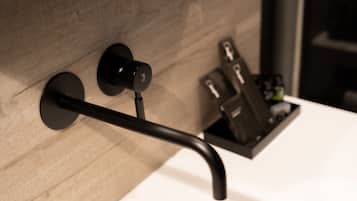 Un baño moderno con pared de madera, grifo negro y toallero negro.