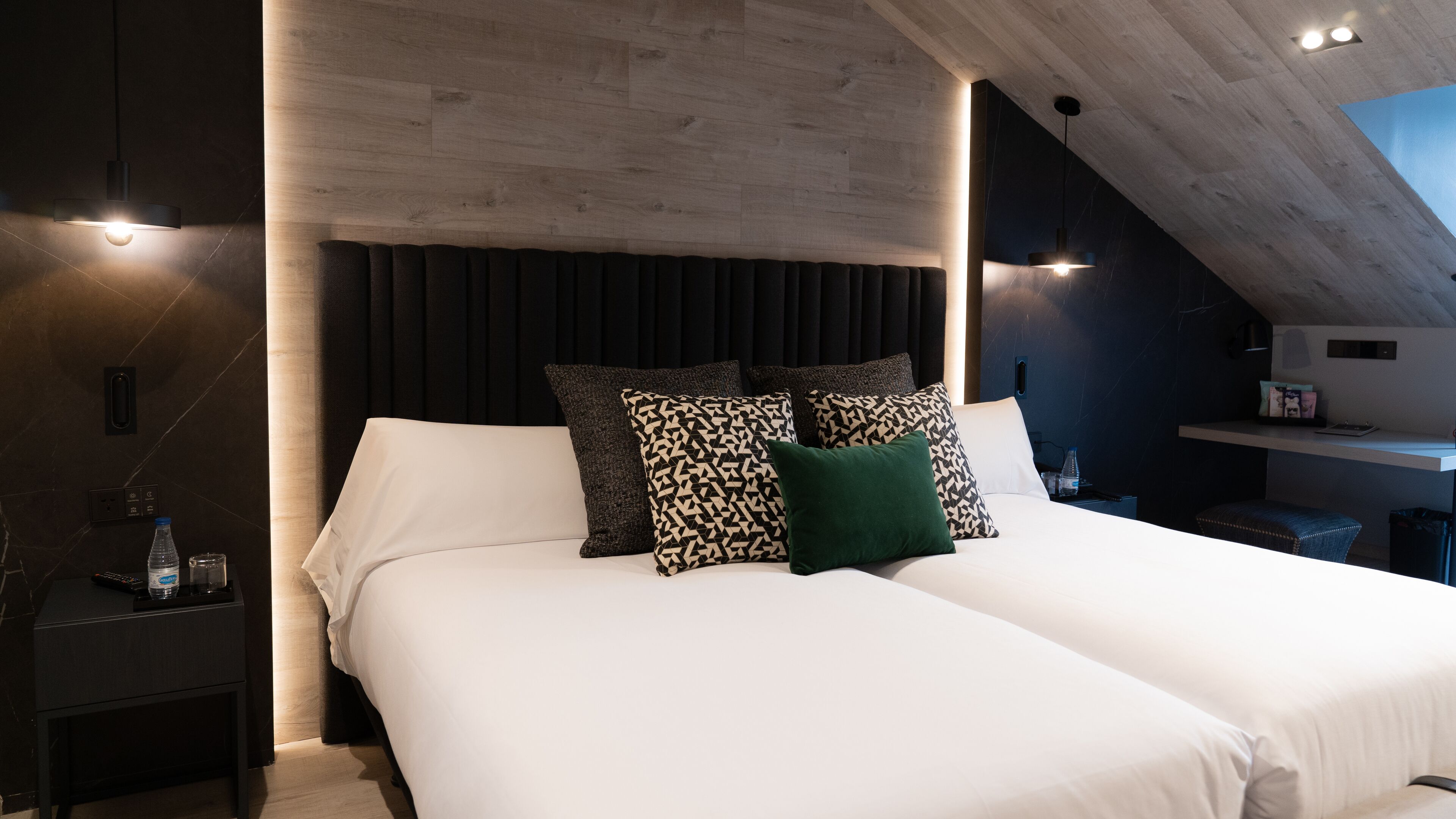 Camera da letto moderna con un letto grande, tende scure e un soffitto in legno.