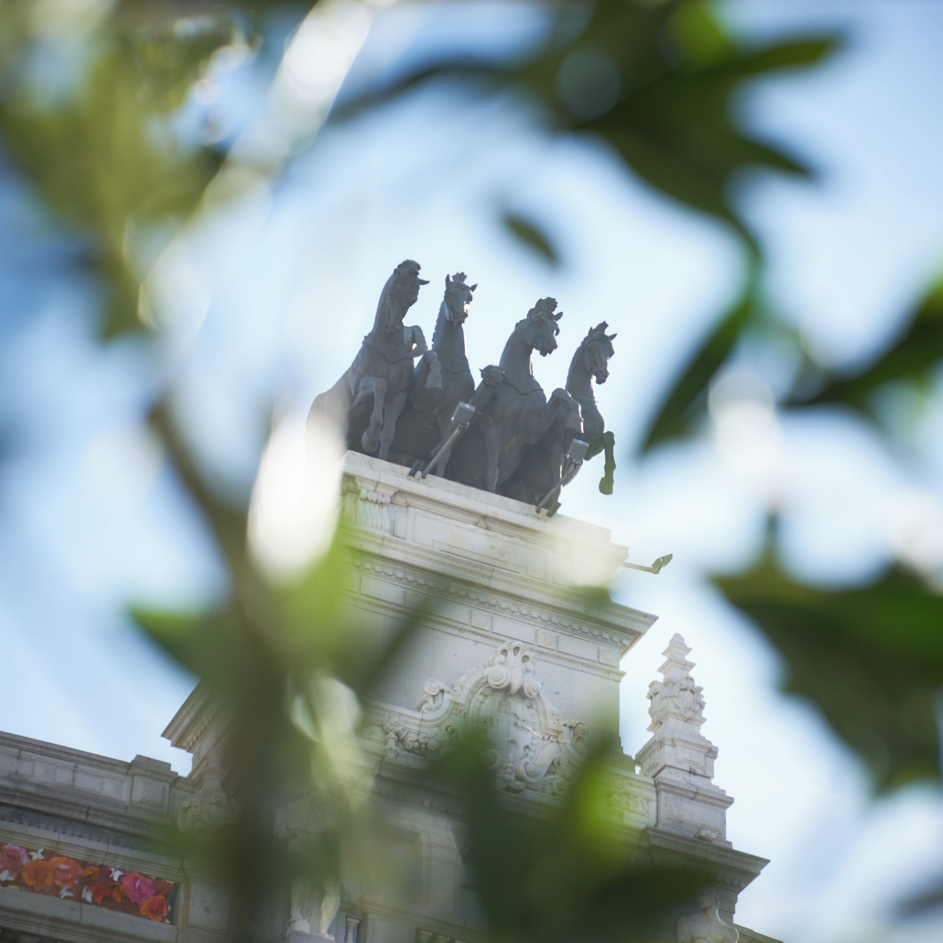 A statue of four figures on horseback atop a classical building with ornate architectural details.