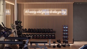 Un gimnasio con equipo de levantamiento de pesas, un letrero motivacional y una pared de madera.