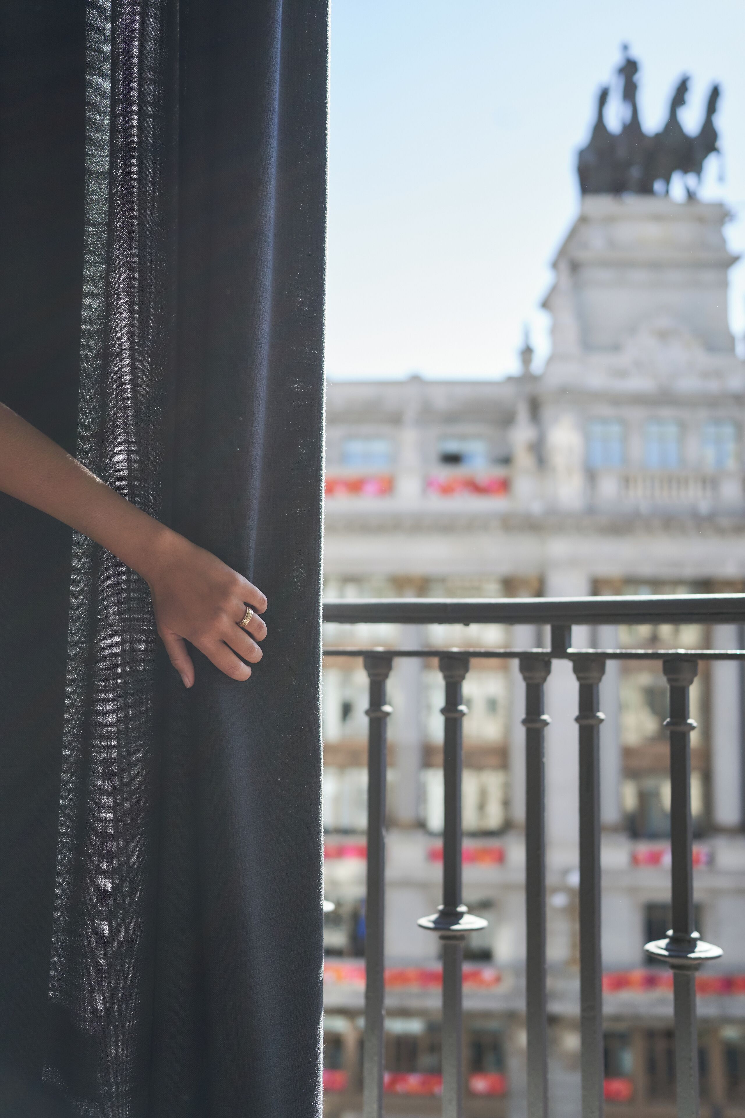 A balcony with a metal railing and a view of a building with a statue.